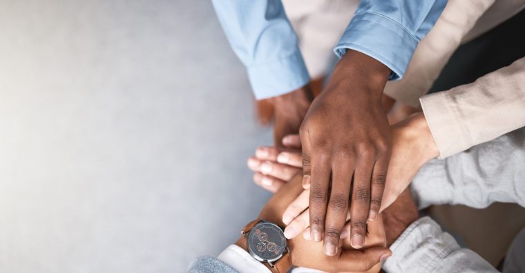 les mains de plusieurs personnes regroupées en cercle posées les une sur les autres en signe de pouvoir collectif